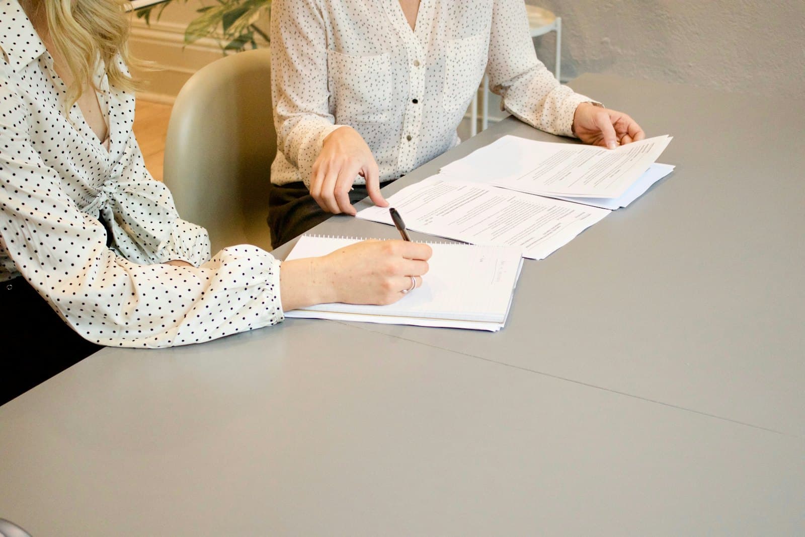 Two people at a table reviewing and signing a set of printed documents